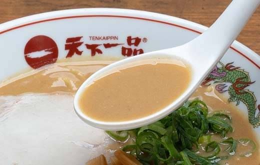 ラーメンのスープをレンゲですくっている