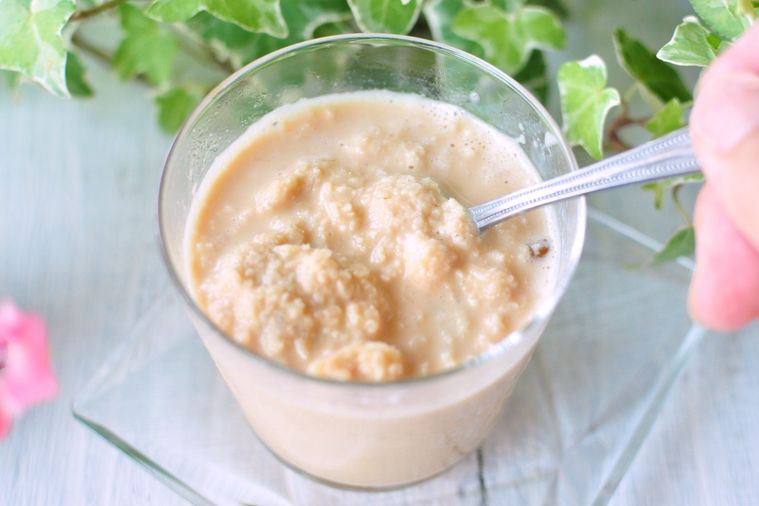 グラスに入った紅茶氷とミルクをスプーンで混ぜる様子