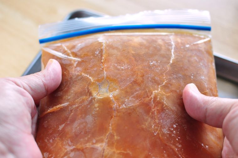 ジッパー付き保存袋の中の凍った紅茶を外側から手で割って砕く様子