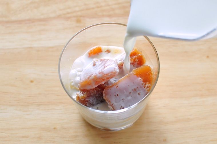 紅茶氷が入ったグラスにミルクを注ぐ様子