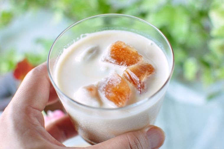 紅茶氷とミルクが入ったグラスを手で持ち上げている様子