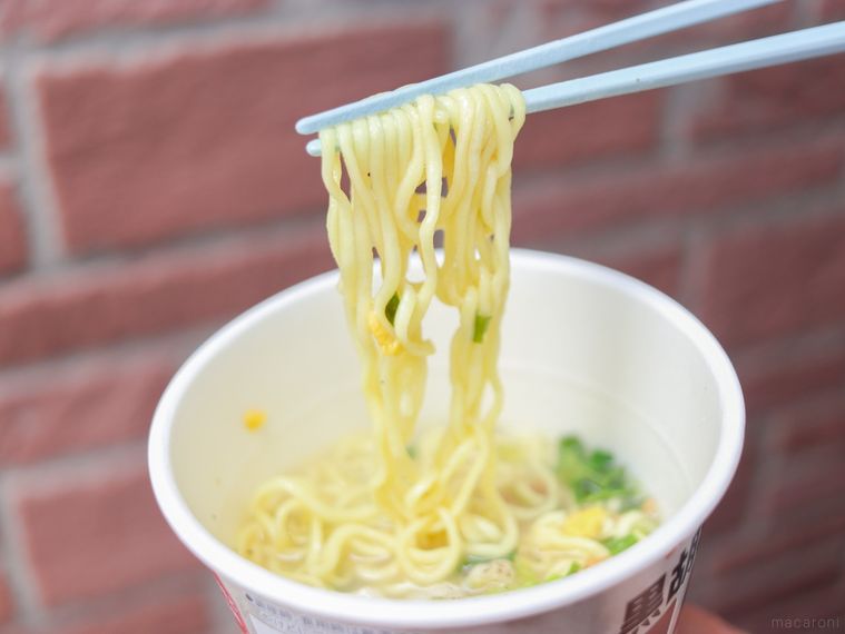 黒胡椒コムタンラーメンの麺を水色の箸で持ち上げている