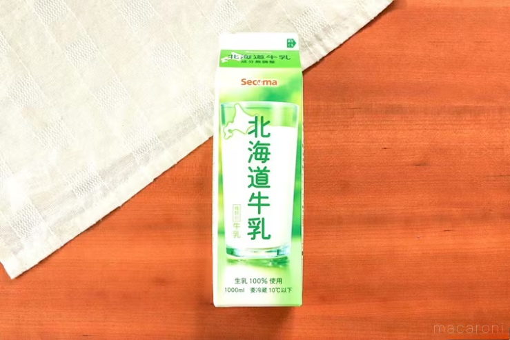 白いランチョンマットを斜めに敷いた木製のテーブルに北海道牛乳が置かれている