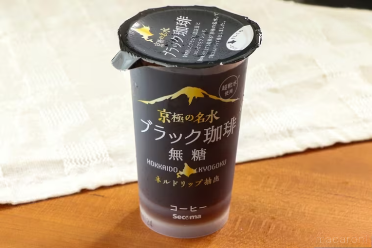 白いランチョンマットを斜めに敷いた木製のテーブルの上に置かれた京極の名水ブラック珈琲