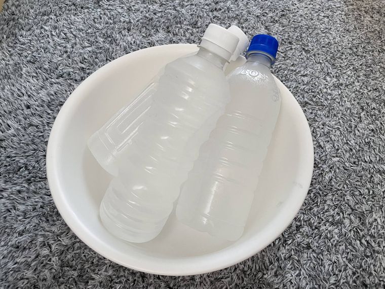 白い洗面器に置かれた3本の水入りペットボトル