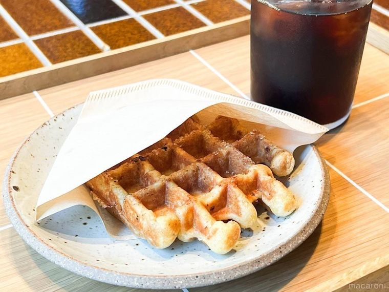 白い皿に盛られたリエージュワッフルと細長いグラスに入ったコールドブリュー