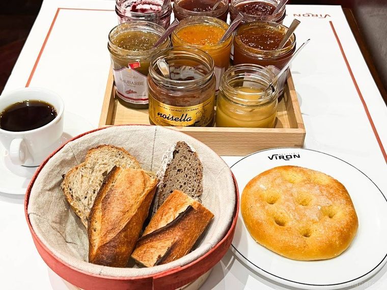 カゴに入ったパンと白いお皿に入ったヴィエノワズリー。6種類のジャムとチョコレートペースト、はちみつ