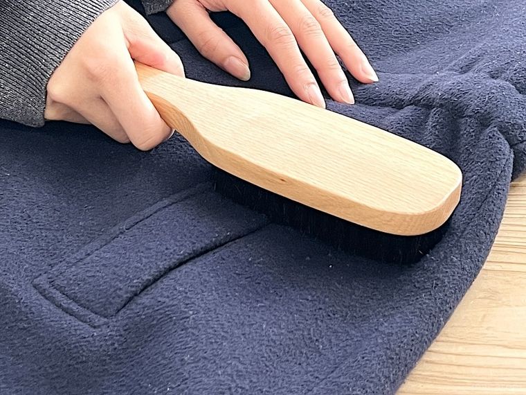 ブナ材洋服ブラシでコートの毛玉を取っている様子