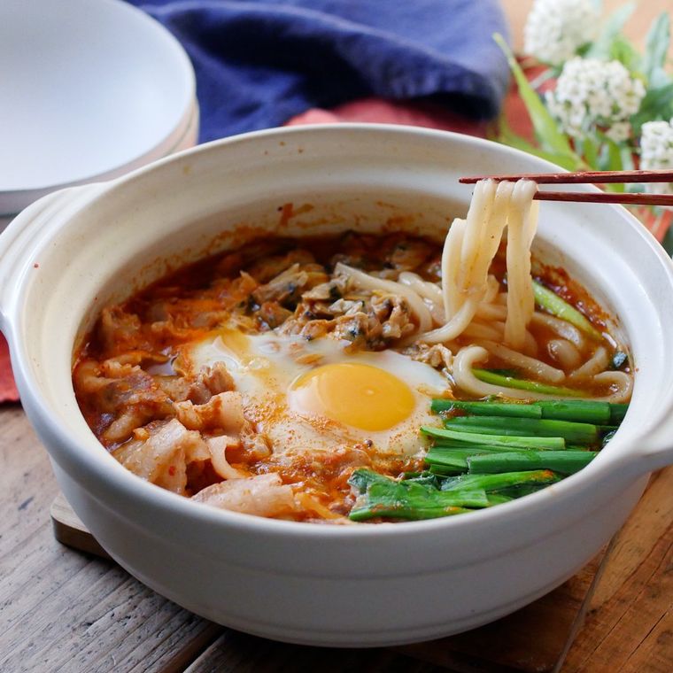 白い小鍋に入っている豚キムチとあさりの煮込みうどん