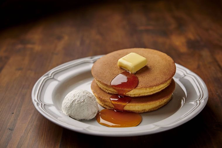 バター、シロップ、ホイップクリームが添えられたホットケーキ