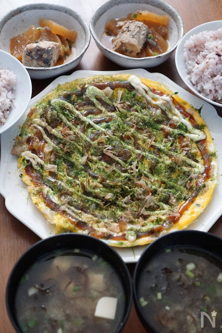 豆苗と豚肉のとん平焼き風のまわりに並べられたご飯と味噌汁とおかず