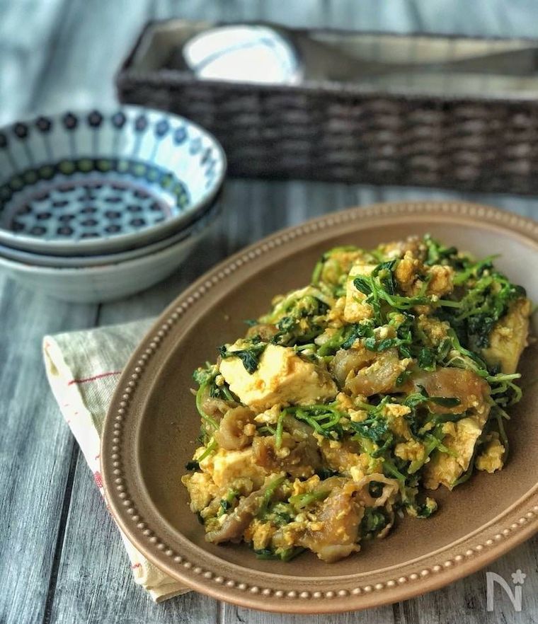 茶色の器に盛られた豆苗のカレーチャンプルーと取り皿