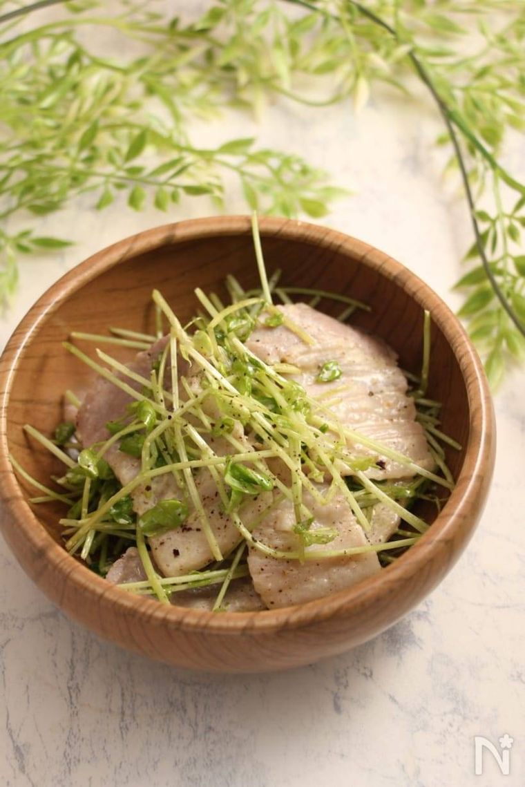 木製の丸い器に盛られた塩豚と豆苗のサラダ