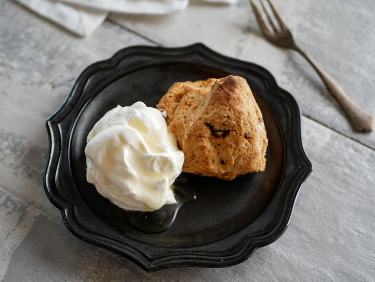 黒いデザインリムプレートにのったコストコアイリッシュスコーンとホイップした生クリーム