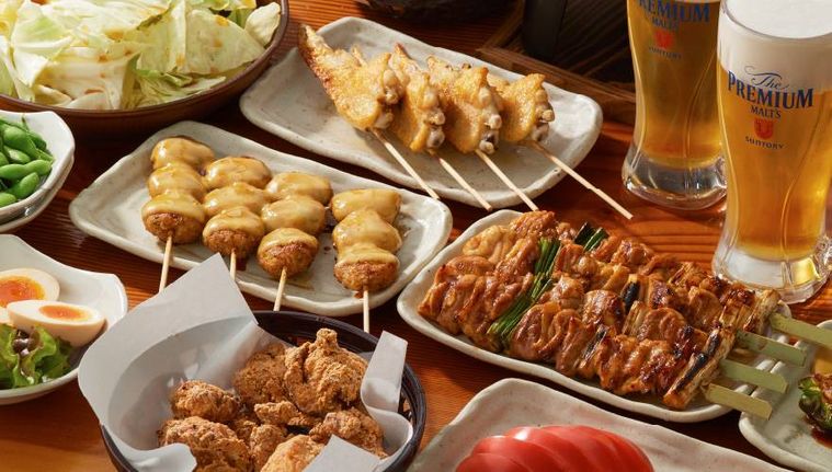 テーブルの上に焼鳥や唐揚げ、ビールなどが並んでいる