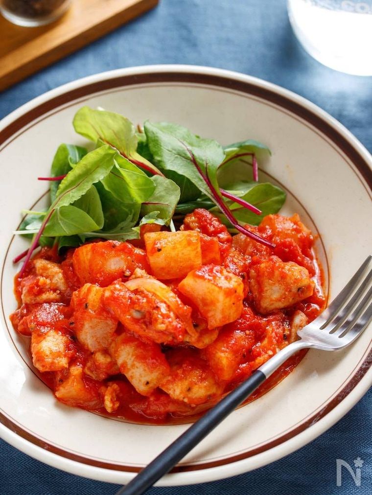 丸い器に盛られた鶏大根のトマト煮とフォーク