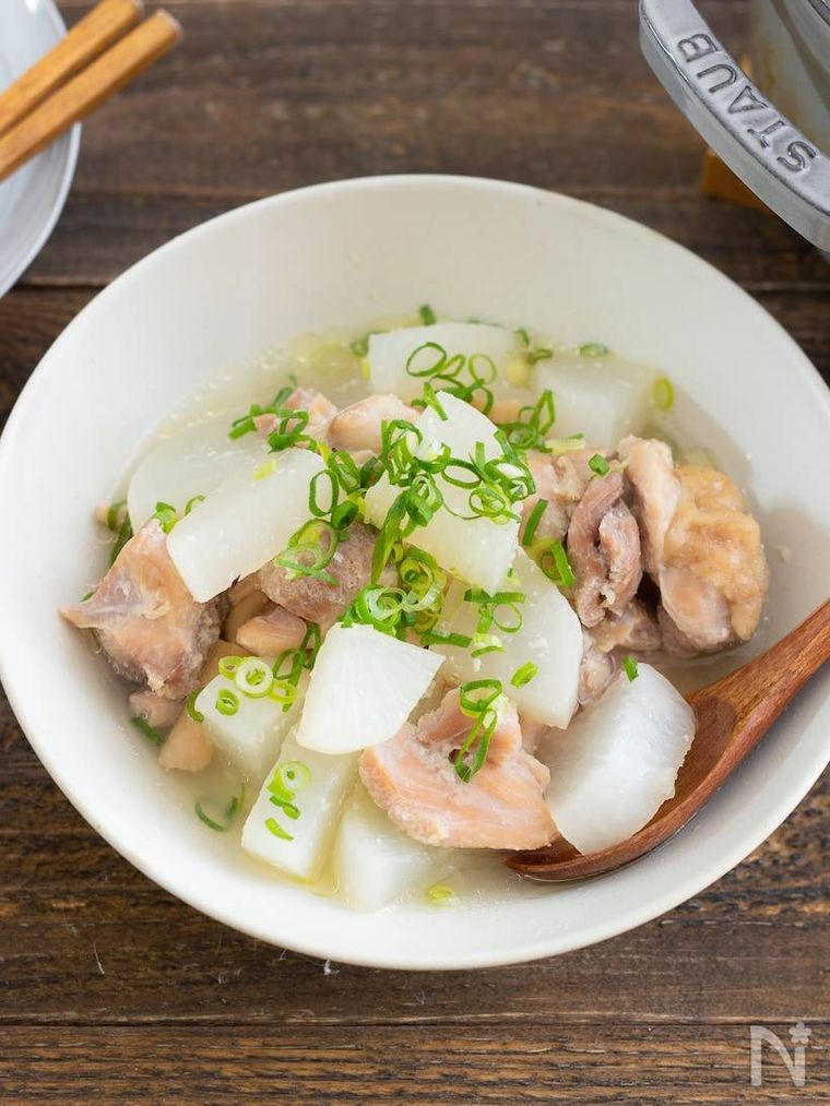 木製のテーブルと白い器に盛られた鶏もも肉と大根の塩麹煮込み