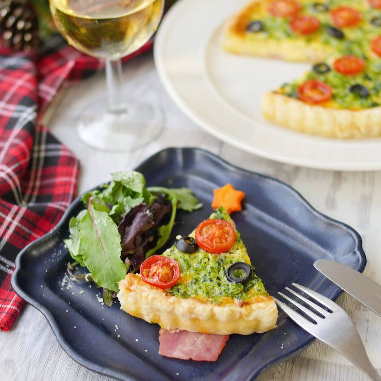 紺色の皿に盛られたブロッコリートマトのクリスマスキッシュ