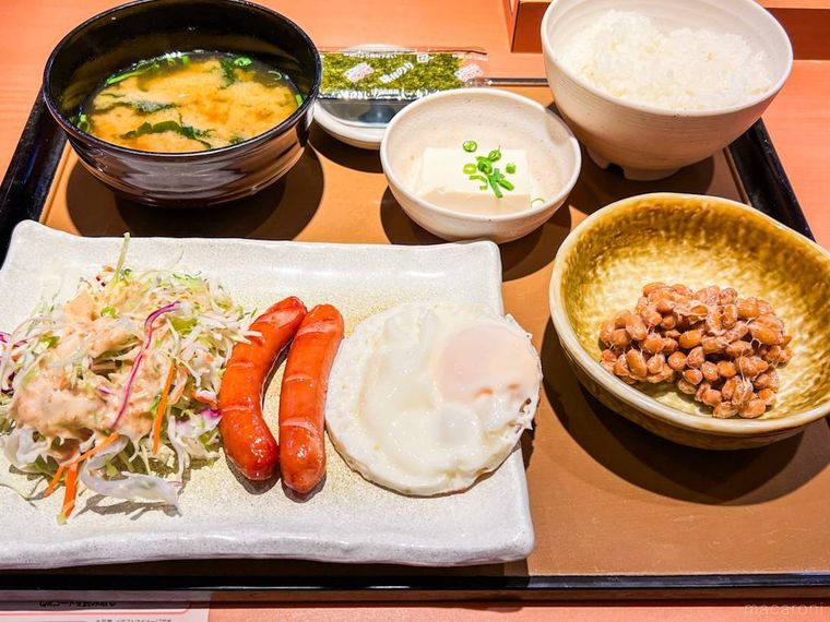 木のお盆に並べられた、小針やお皿に盛られたエッグウインナー朝食