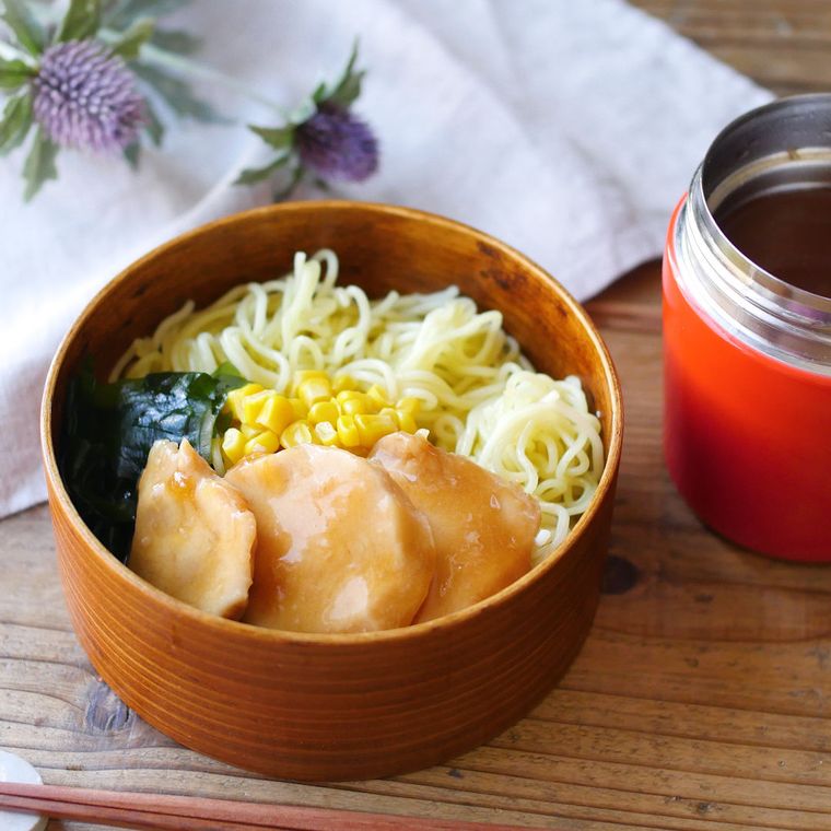 曲げわっぱの弁当箱に麺と鶏チャーシュー、コーン、わかめが入っている