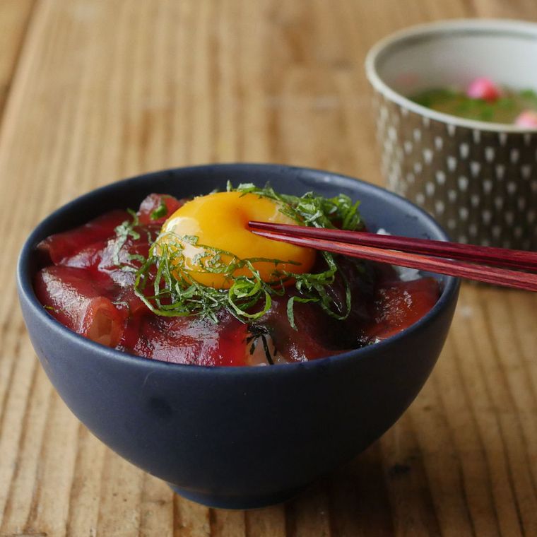 まぐろ丼の卵黄をお箸で潰そうとしている様子