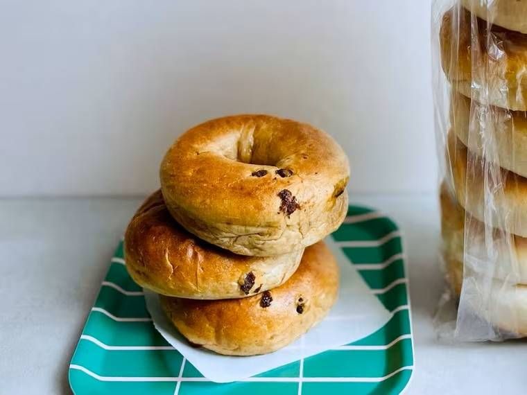 緑色のプレートのうえに、レーズンの含まれたベーグルが3個重なっている