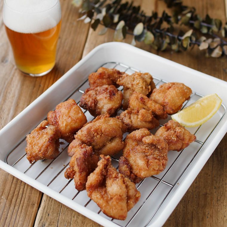 白い油切りバットの網の上に並べられた鶏もも肉の唐揚げ