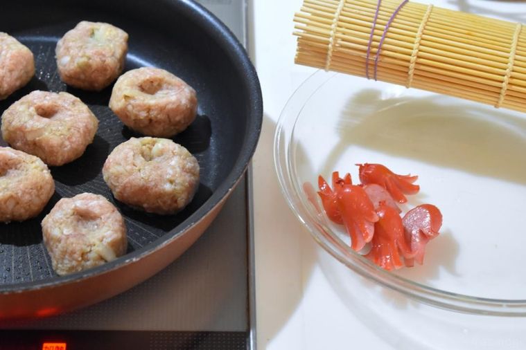 ハンバーグをを調理中のフライパン、皿に並べたウインナー