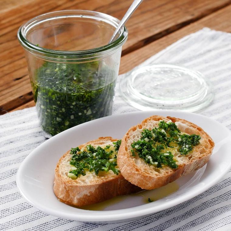 瓶に入ったパセリのガーリックオイルと白い皿にのったフランスパン