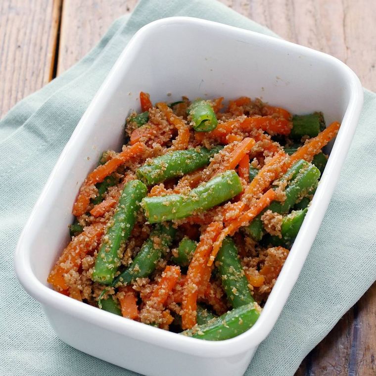 白い保存容器に入ったさやいんげんとにんじんのごま和え