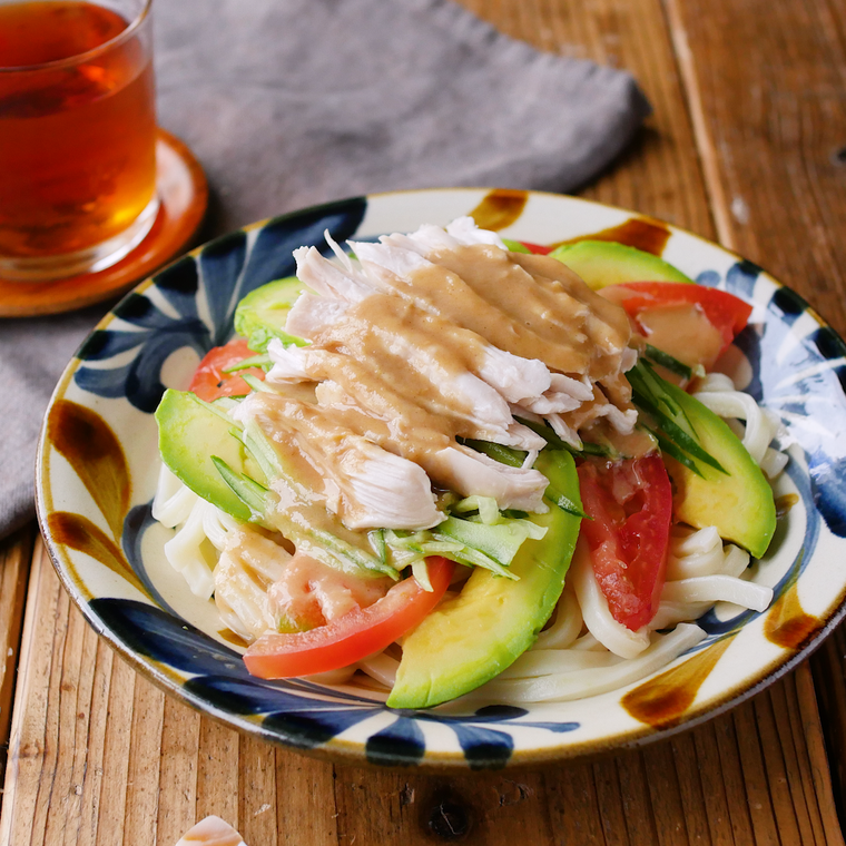 柄のある皿に盛りつけた鶏むね肉とアボカドのサラダうどん