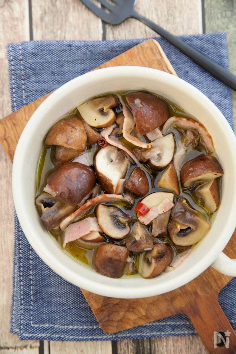 木製のカッティングボードにのせられたマッシュルームのアヒージョ