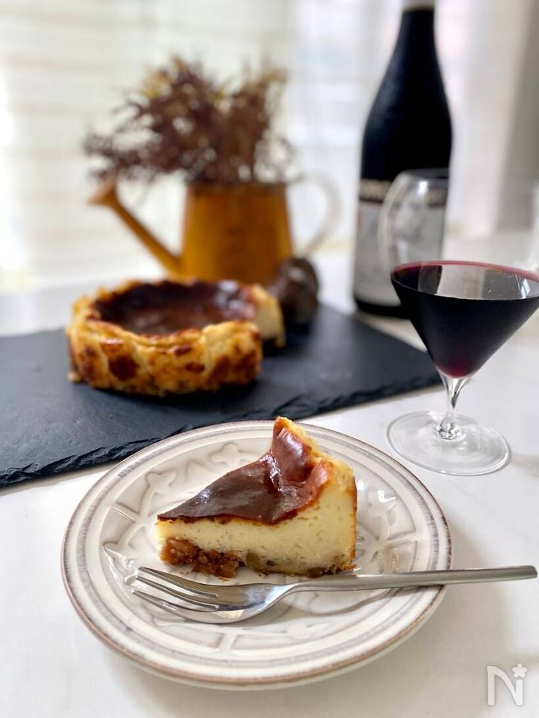丸い器にのせられたゴルゴンゾーラベイクドチーズケーキと赤ワインが並ぶ様子