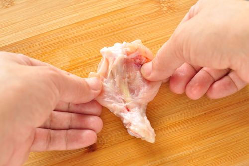 切り込みを入れた手羽元を手で開く様子