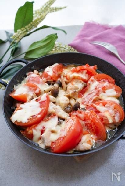 黒いスキレットにのせられた鶏むね肉とトマトのチーズ焼き