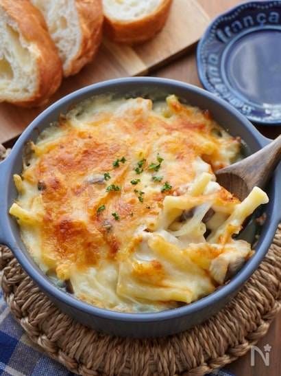 青いココットに入った鶏むね肉とチーズのきのこグラタンと木製のスプーン