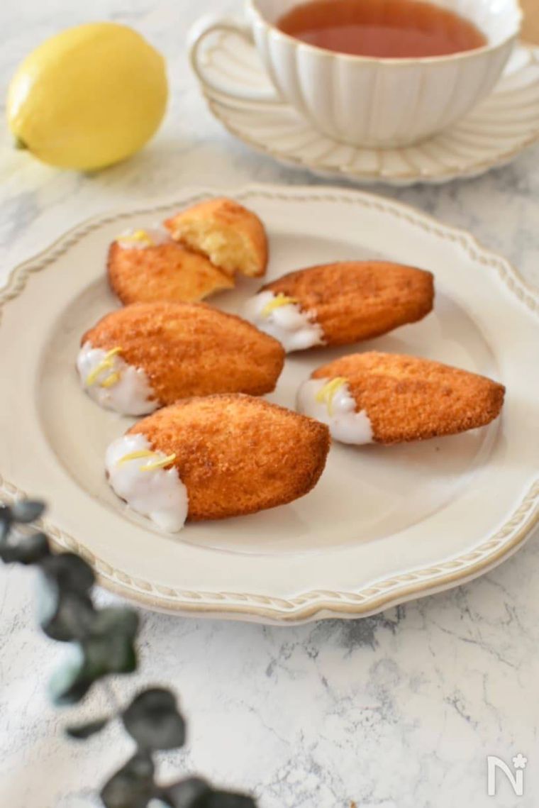 ベージュの器に置かれたレモンたっぷりマドレーヌ