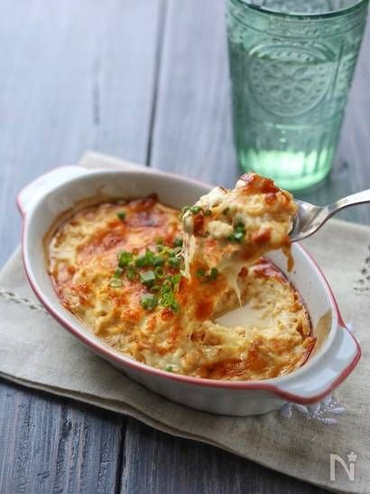 白い耐熱容器に入った豆腐ツナグラタンをスプーンですくっているところ