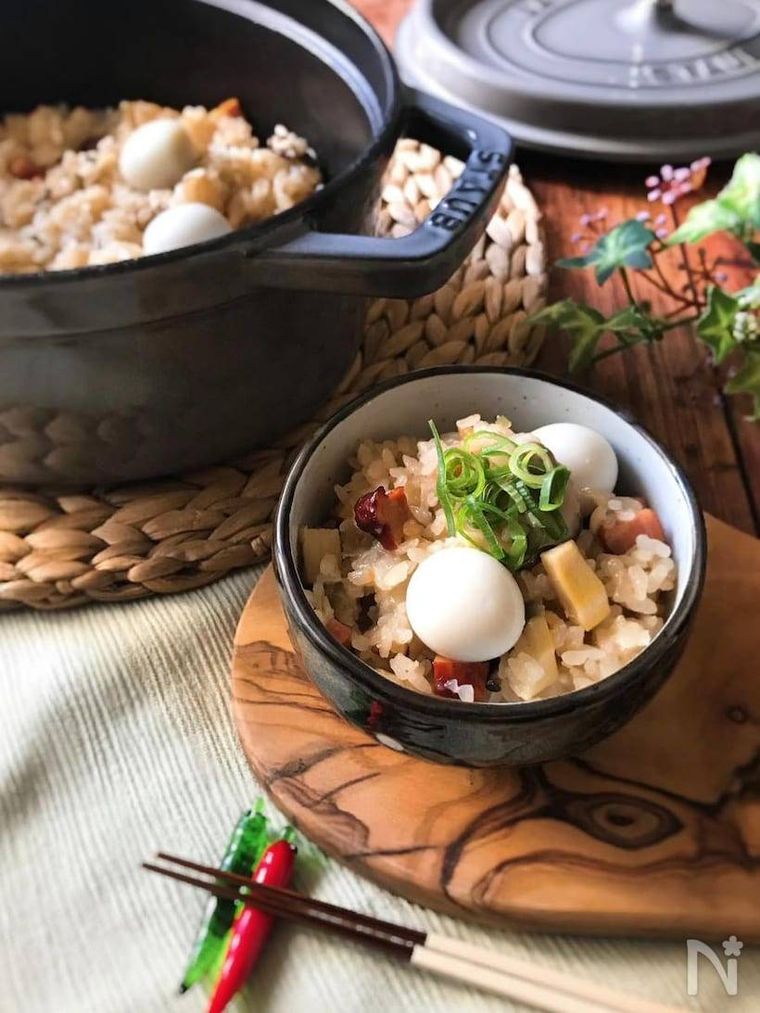 黒い茶碗に盛られたごま油香る中華おこわ。傍らにおこわが入ったストウブ鍋がある