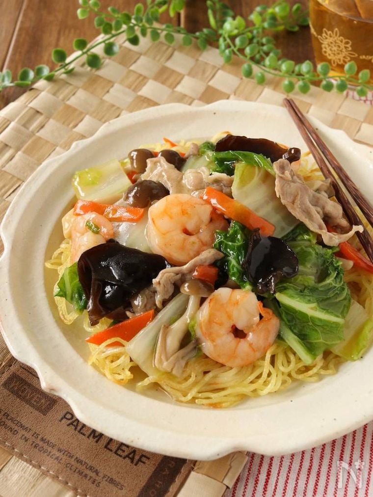 白い器に具だくさんのあんかけ焼きそばが盛られていて、傍らに箸が置かれている