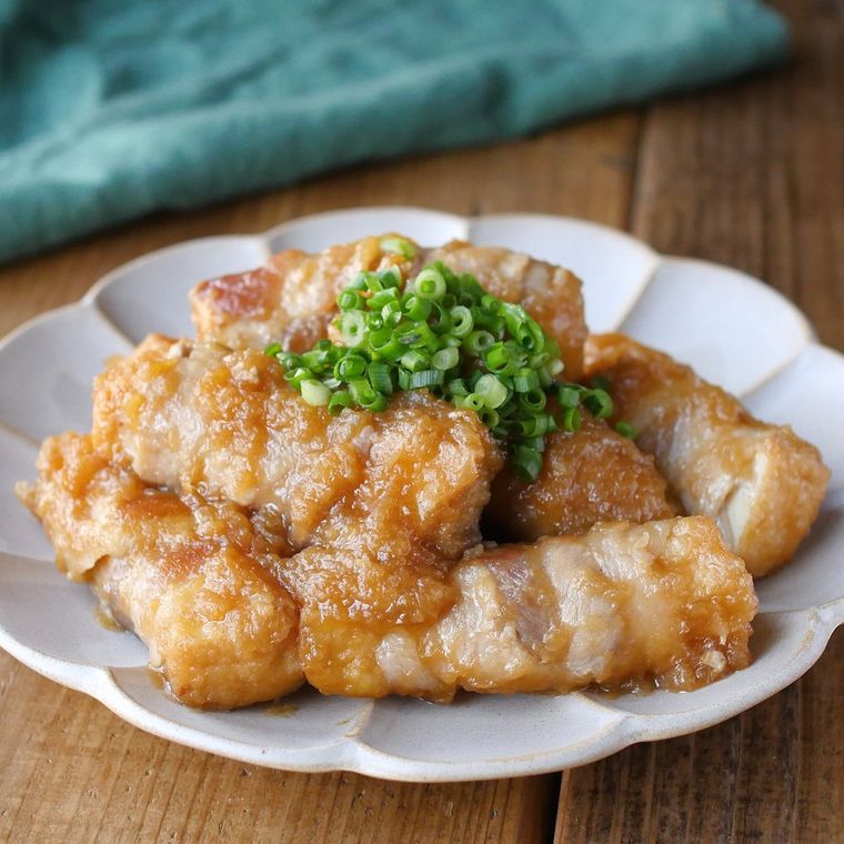 花びら形の白い皿に盛りつけられた肉巻き厚揚げのおろし玉ねぎ煮