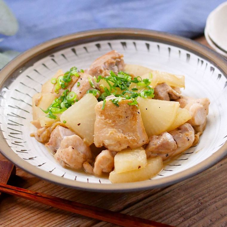 縁取りのある皿に盛りつけられた大根と鶏肉のバターしょうゆ炒め