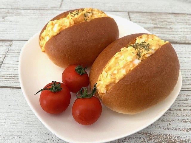 バターロールの卵サンドとミニトマトが皿にのっている