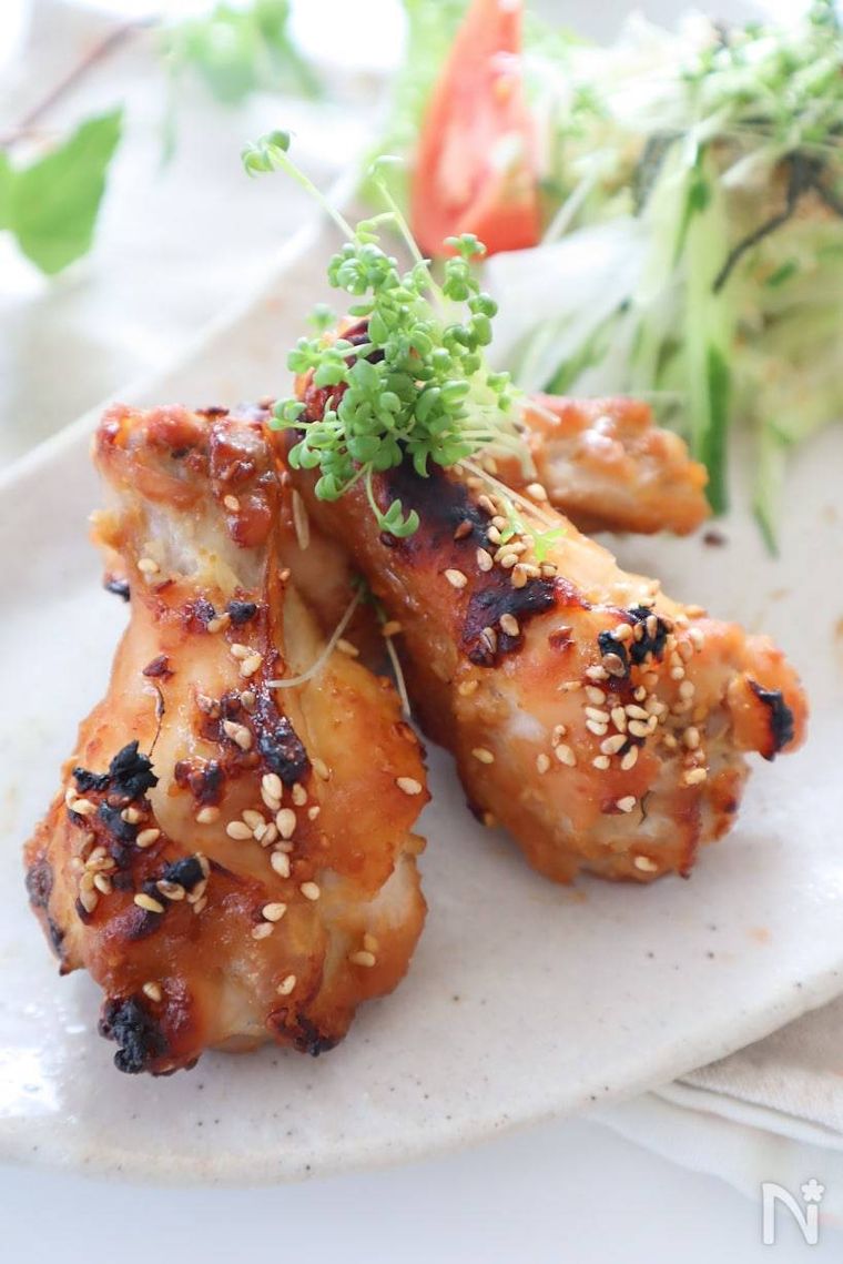 楕円形の器に盛られた鶏手羽元のにんにく味噌グリルとサラダ