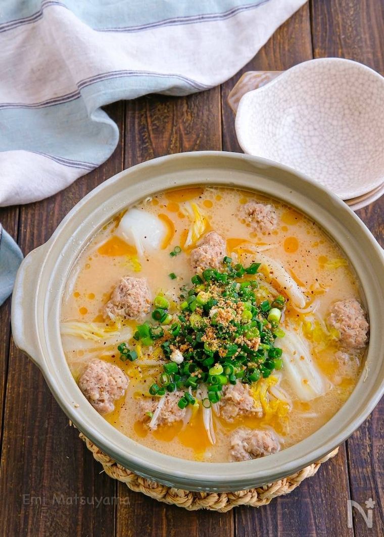 鍋敷きに置かれたえのき豚団子の豚骨風豆乳鍋と3枚の取り皿