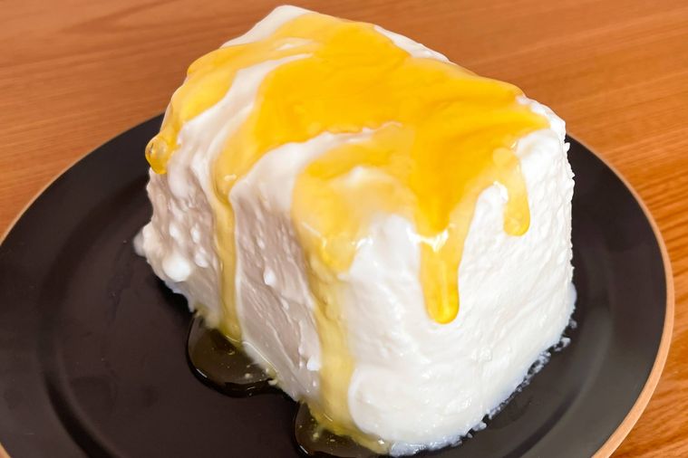 お皿の上にはちみつのかかった丸ごとヨーグルトのレアチーズケーキがのっている