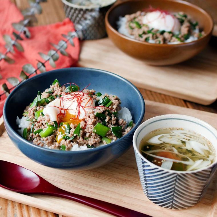 青い器に盛り付けた豚ひき肉とニラのスタミナ丼と和食器に盛り付けた梅わかめスープ