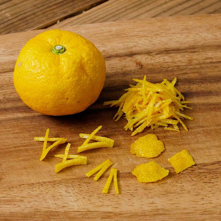 木のボードにおかれた丸ごとゆず、ゆずの皮をカットしたもの