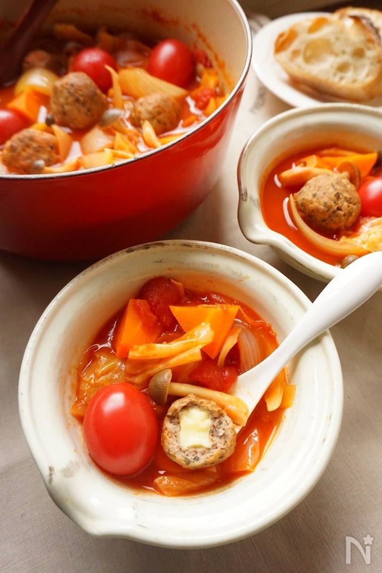 赤い鍋に入れられたチーズミートボールのトマト鍋を小皿に取り分ける様子