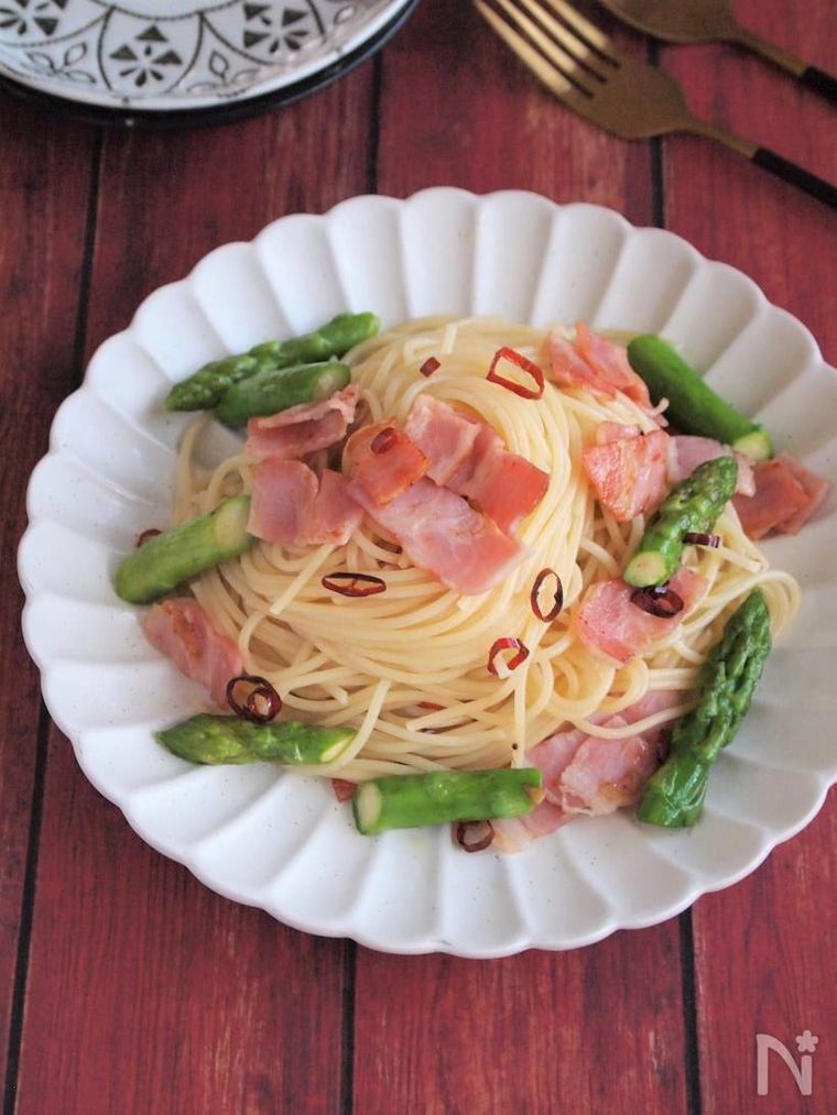 白いスカラップ皿に盛り付けられたアスパラガスとベーコンの簡単ペペロンチーノ